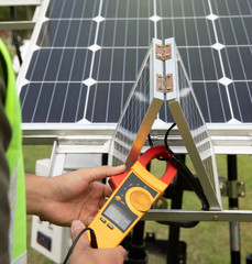 An engineer working on checking equipment in solar power plant. Electrician is using a digital...