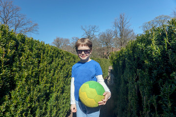 Naklejka premium Five year old boy posing with ball in Bush Labyrinth at Slottsskogen park