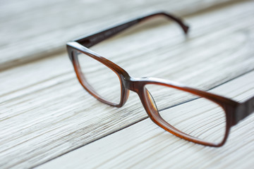 A pair of eyeglasses sits on a rustic wooden surface