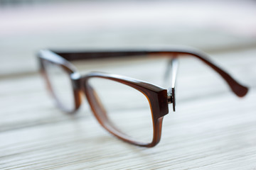 A pair of eyeglasses sits on a rustic wooden surface