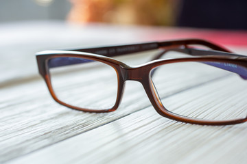 A pair of eyeglasses sits on a rustic wooden surface