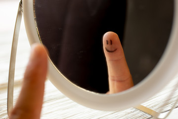 A finger with a happy face looks at himself in the mirror