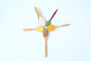 Various colorful powder in different wooden spoons isolated on white background.