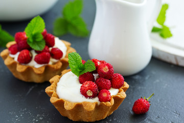 Wild strawberry tartlets with cream filling. delicious summer fruit mini tarts
