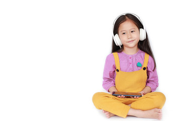 Portrait little Asian girl enjoys listening to music by headphones isolated on white background with copy space.