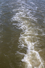 Top view on the water splash behind a fast driving ship on the ocean