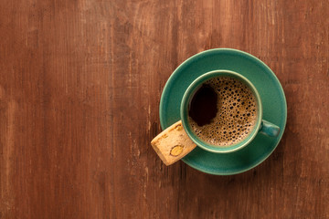 A cup of black coffee with a cookie, shot from above on a dark rustic wooden background with a place for text