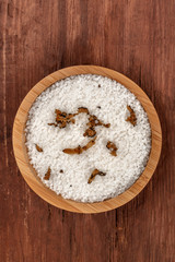 A bowl of sea salt infused with truffle shavings, shot from the top on a dark rustic wooden background with copy space
