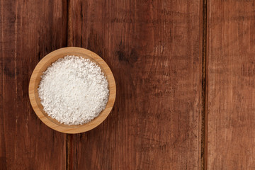 Fototapeta na wymiar A bowl of coarse sea salt, shot from the top on a dark rustic wooden background with copyspace
