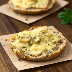 Baked ham, green olive and cheese sandwich with oregano, photographed on dark wood with natural light (Selective Focus, Focus on the front of the olive slices on the first sandwich)