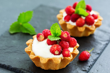 Wild strawberry tartlets with cream filling. delicious summer fruit mini tarts