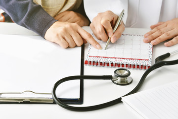 Doctor and patient make an annual health checkup appointment at hospital, Physician finger point at...