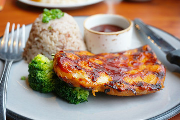 Closeup grill chichen steak with riceberry and source on the dish.