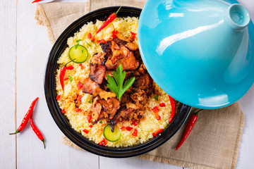 Tajin with couscous, vegetables and meat on white background