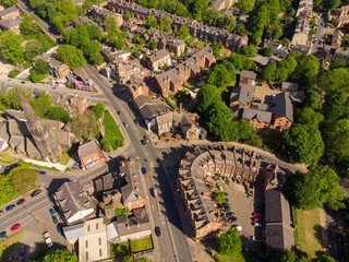 Fototapeta na wymiar Aerial footage of the Leeds town of Headingley, the footage shows Terrence houses and homes and the town centre in the background with roads and traffic, taken on a beautiful sunny day.
