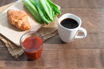 Tomato juice, black coffee, croissant and vegetable on rustic wooden table. Breakfast concept