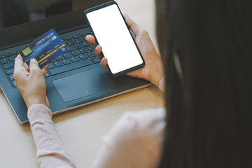 Asian young woman hands holding credit card and using laptop smartphone for online shopping concept