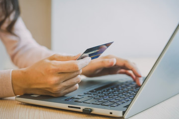Fototapeta premium Close-up woman's hands holding a credit card and using computer keyboard for online shopping concept