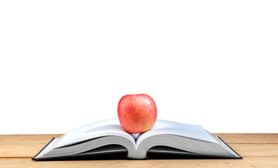 Apple on the middle of opened book on wooden table