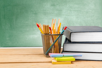 Pile of books with notes paper and pen with pencils in basket container on wooden table with...