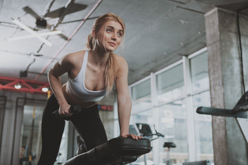 Low angle shot of a gorgeous athletic woman lifting weights at the gym, copy space. Attractive sportswoman doing back muscles workout at sport studio. Body building, lifestyle concept © Ihor