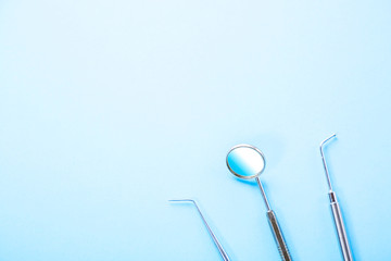 Dentist tools. Professional steel dental instruments with a mirror on blue background with free space. Dental health and teethcare concept.