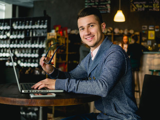 Smiling business man with laptop in cafe