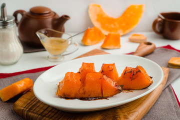 Baked pumpkin with honey and olive oil. Cafe menu on a wooden background in warm colors with copy space.