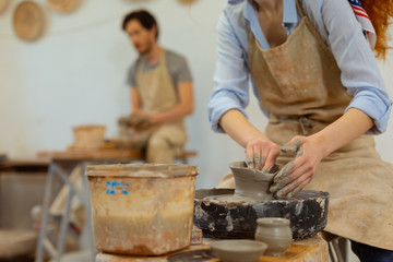 Ginger curly girl in grey apron molding tall pot