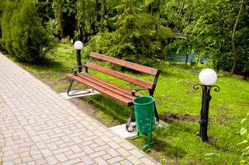 brown wooden bench near the alley in the park. Summer is outside, the sun is shining