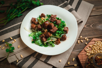 Braised beef with parsley, cucumbers, pine nuts and sweet onions. Cafe menu on a wooden background...