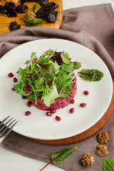 Beet salad with pomegranate, walnuts, prunes and spinach. Cafe menu on a wooden background in warm colors with copy space.