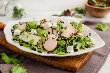Salad with chicken breast, arugula, lettuce, homemade cheese and balsamic sauce. Cafe menu on a wooden background in warm colors with copy space.