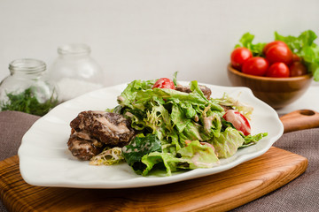Salad with beef, lettuce, cherry tomatoes, and mayonnaise dressing. Cafe menu on a wooden background in warm colors with copy space.
