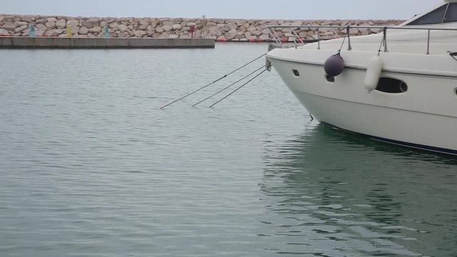 Pan shot on tiny breakwater and a boat anchored in Rodi Garganico marina, Italy