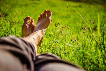 Chilling in the green grass: Legs of a young man, relaxing, summertime