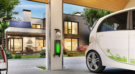 Charging an electric car in the garage near the house. Modern house with solar panels on the roof.