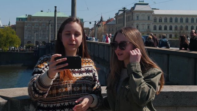 Two young traveling women standing on the bridge and looking at the lockscreen
