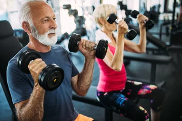 Fototapeten Reifes, fittes Paar, das im Fitnessstudio trainiert, um gesund zu bleiben © NDABCREATIVITY