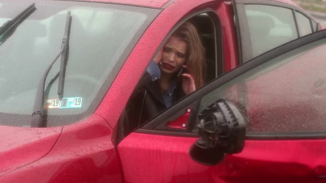 Close-up of the girl talking on the phone after a car accident, she was injured and asks for help. Car accident in the rain on a wet road.
