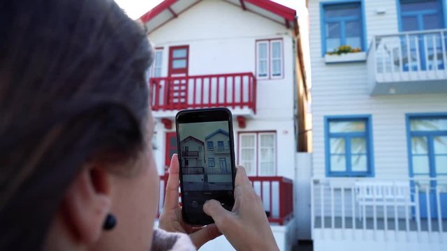 slow motion video of a caucasian woman recording with her phone on the beach.  female tourist taking pictures at the city Aveiro in Portugal. Famous beach for the striped colorful houses.