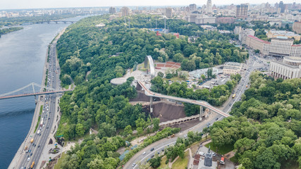 Aerial drone view of new pedestrian cycling park bridge construction, hills, parks and Kyiv cityscape from above, city of Kiev skyline, Ukraine