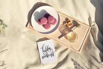 Many colored french macaroons or macaroon on a wooden tray a jar of honey and a round wooden spoon for honey.