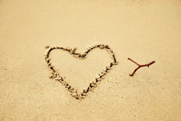 Heart shaped symbol on a sandy beach in summertime.