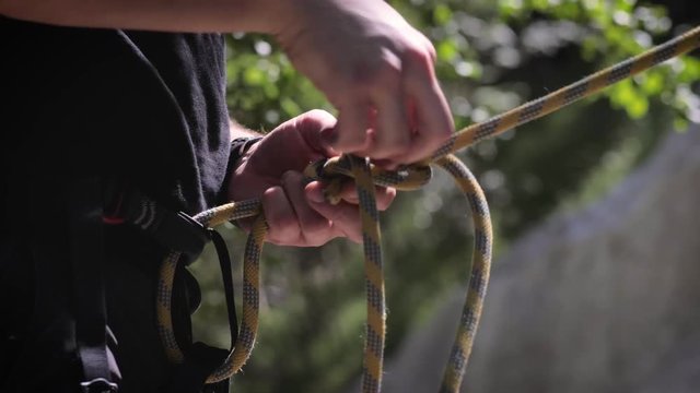 Climber makes a knot with the rope