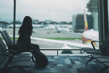 A woman traveler sitting and waiting with backpack at the airport