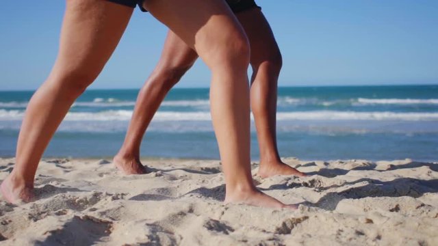 Detail of foot of women walking on the beach sand in slow motion