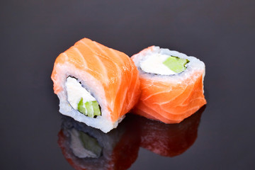 Philadelphia roll sushi with salmon, avocado and cream cheese on black background for menu. Japanese food