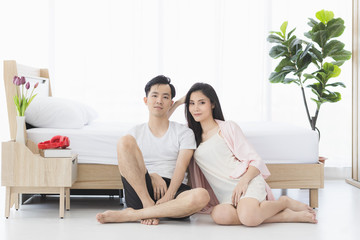 Sexy couple in pajamas sit on floor in bedroom..