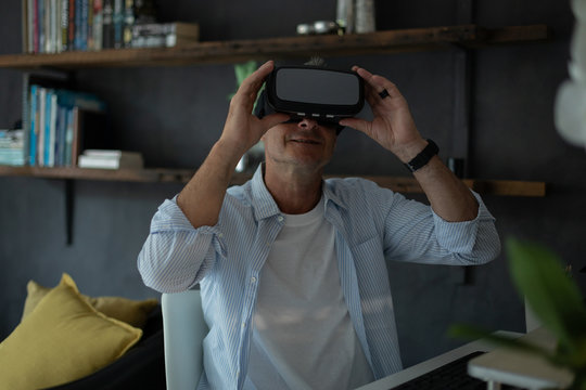 Mature man using virtual reality headset in living room